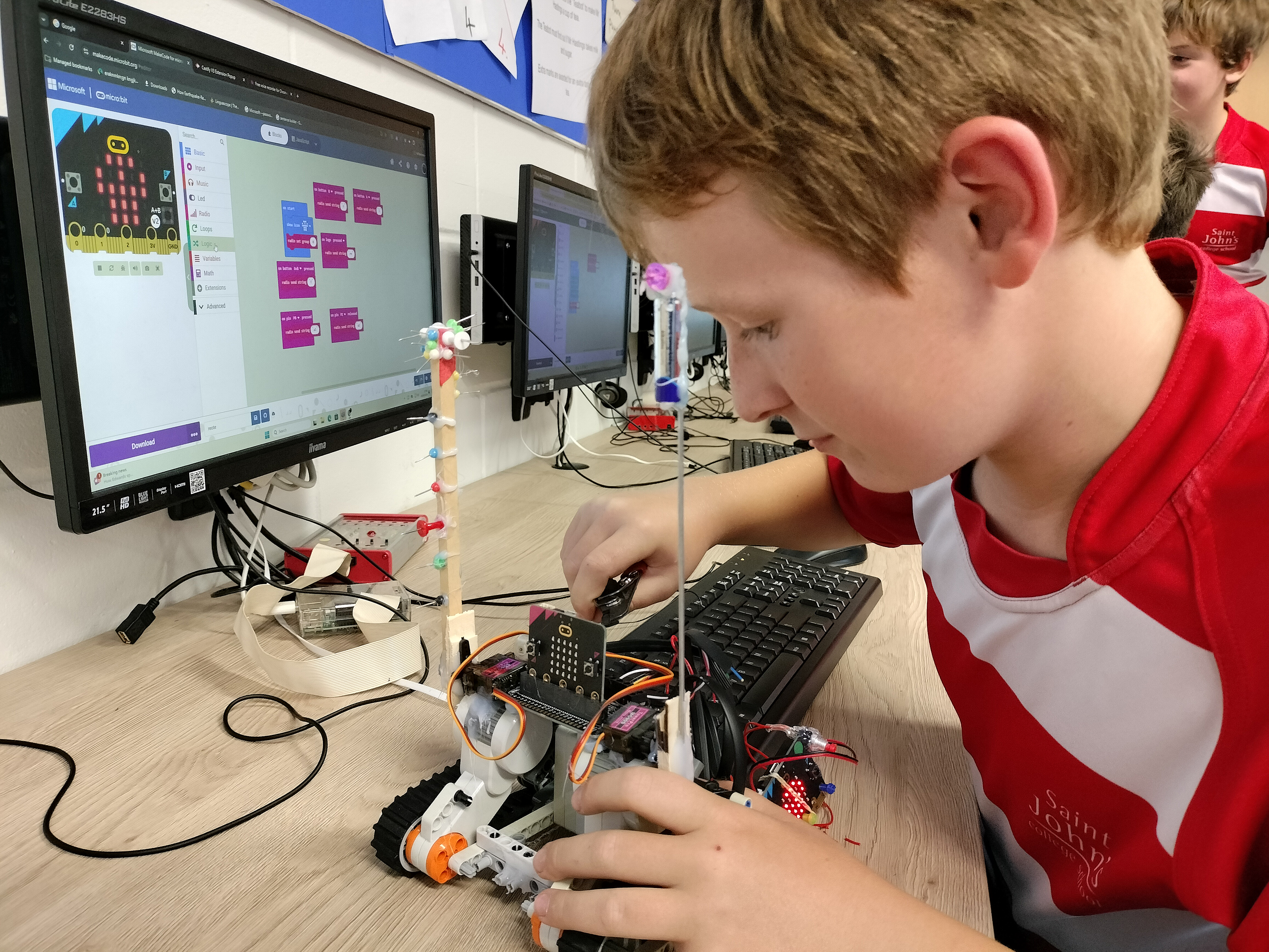 boy working in front of a computer on a robotic model