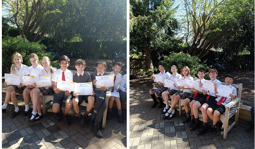 children sitting on a bench holding up winning certificates