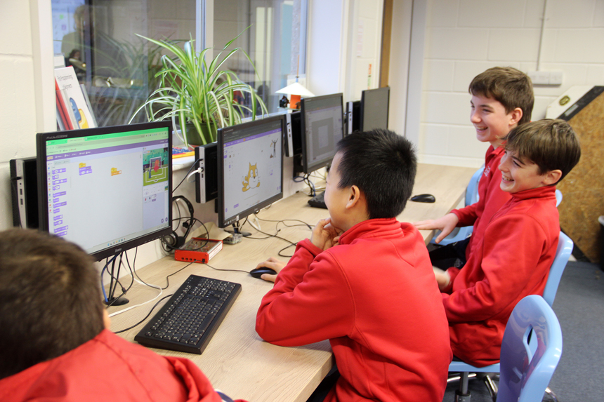 children working on coding on computers in a room