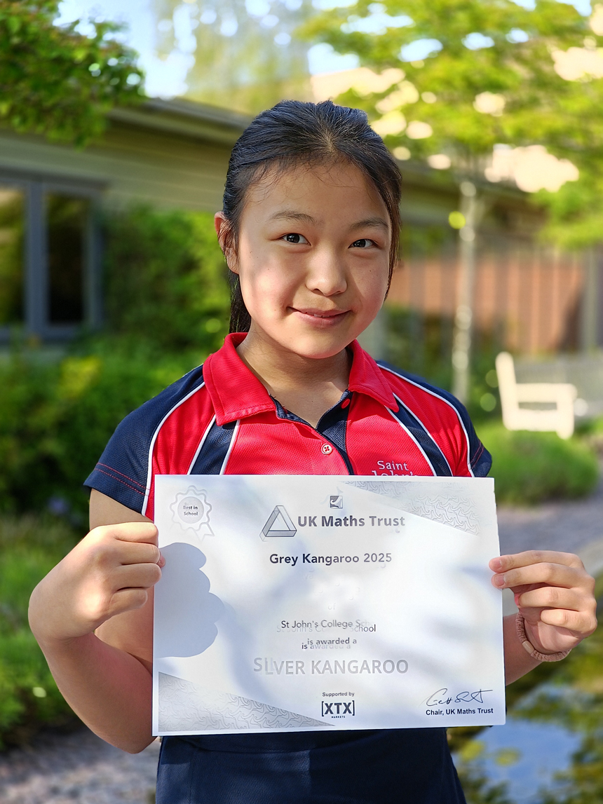 pupil holding a maths certificate outside