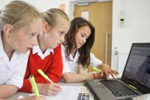 Three students looking at a laptop