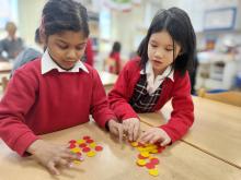two girls working on a maths investigations together in a classroom