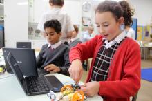 children working on laptops and microbit computers in a room
