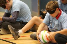 child playing seated handball with a blindfold on