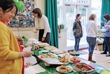 People standing around a table of cakes