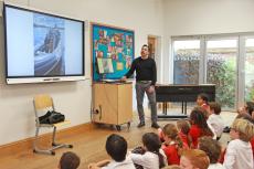 man talking by an interactive board with children in front