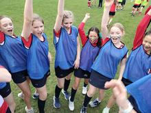 children in sports kit raising their right arms to cheer the start of a race