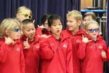 Children standing side by side performing a poem with actions