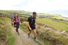 men running on a road across a hill