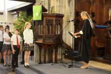 children in a church with a head teacher reading from a lecturn