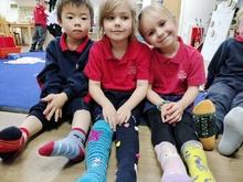 Three children sitting on the floor with legs stretched out to show their mismatching socks