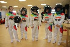 5 children in racing car suits and helmets