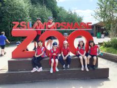 children sitting by a sign for whipsnade zoo