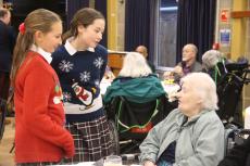children talking to an older guest at a christmas party in a hall