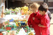 Two children standing in front of a table covered in harvest festival competition contriibutions