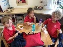 3 children sitting at a small table eating soup