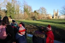 children dressed in coats and hats walking along the backs in Cambridge on a cold winter's day