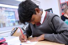 Boy sitting at a table drawing on a piece of paper