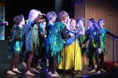 children acting on a stage in costumes