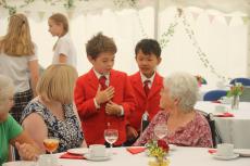 2 children in blazers talking to 2 senior citizens