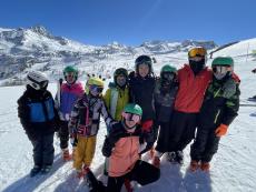 children dressed in ski gear at the top of a snowy mountain