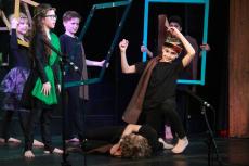 children standing on the stage in costumes performing a greek myth