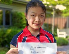 pupil holding a maths certificate outside