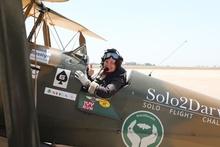 pilot sitting in the pilot's seat of a vintage open-top biplane