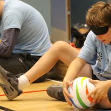 child playing seated handball with a blindfold on