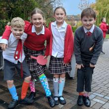 four children wearing odd socks and smiling in a playground