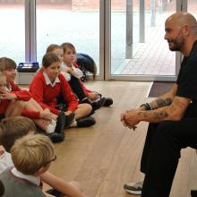children sitting on the floor in a hall listening to a poet talking