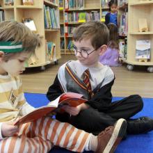 two boys sitting on the floor looking at books