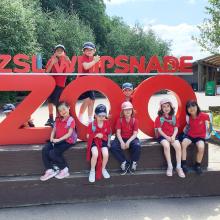 children sitting by a sign for whipsnade zoo