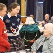 children talking to an older guest at a christmas party in a hall