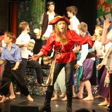 children acting on a stage dressed in pirates costumes
