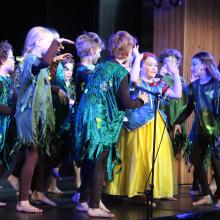 children acting on a stage in costumes