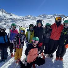 children dressed in ski gear at the top of a snowy mountain