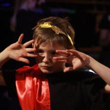 boy with hands over his face dressed as a roman