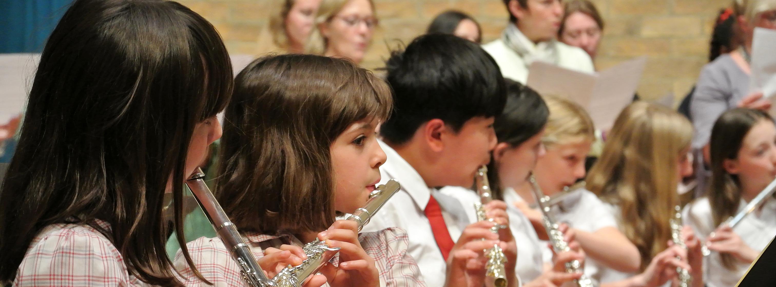 five children playing the flute in a concert